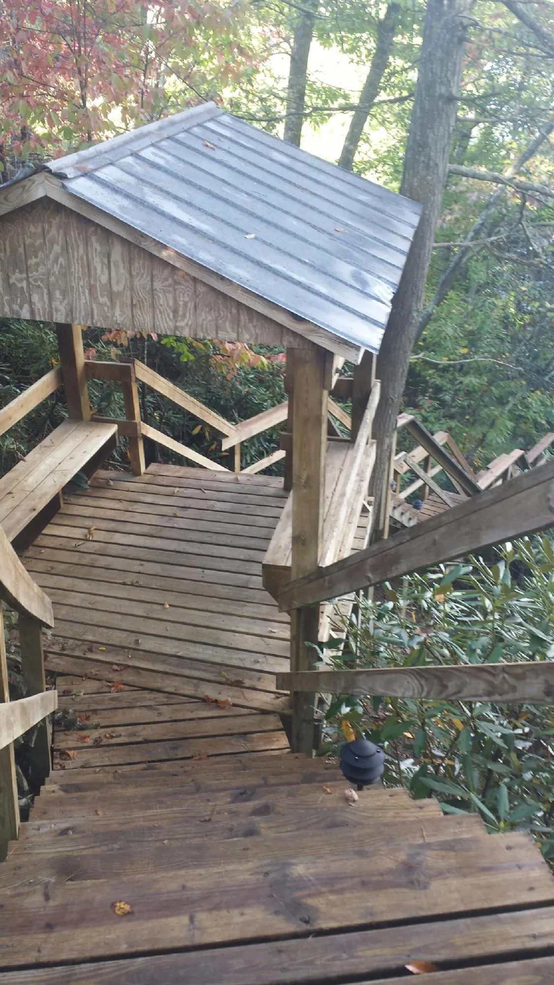 Metal roofed shelter over wooden steps on a wooded walkway — Skylight Repair & Installation work by our crew in Perry